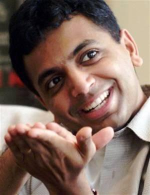 A close up picture of M. Night Shyamalan smiling, and holding his hands together.